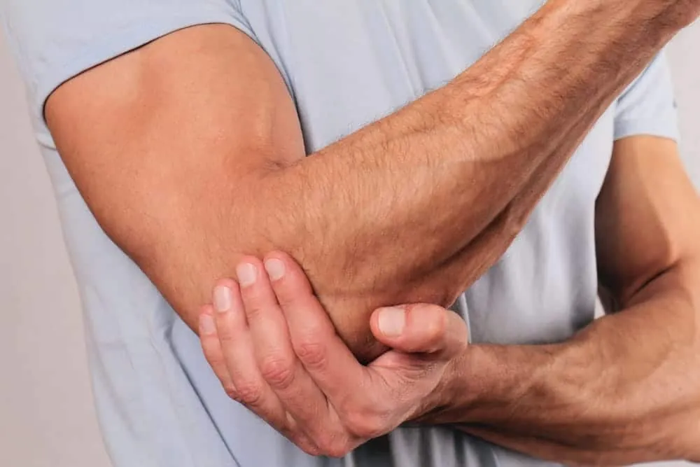 Person holding a sore elbow and forearm