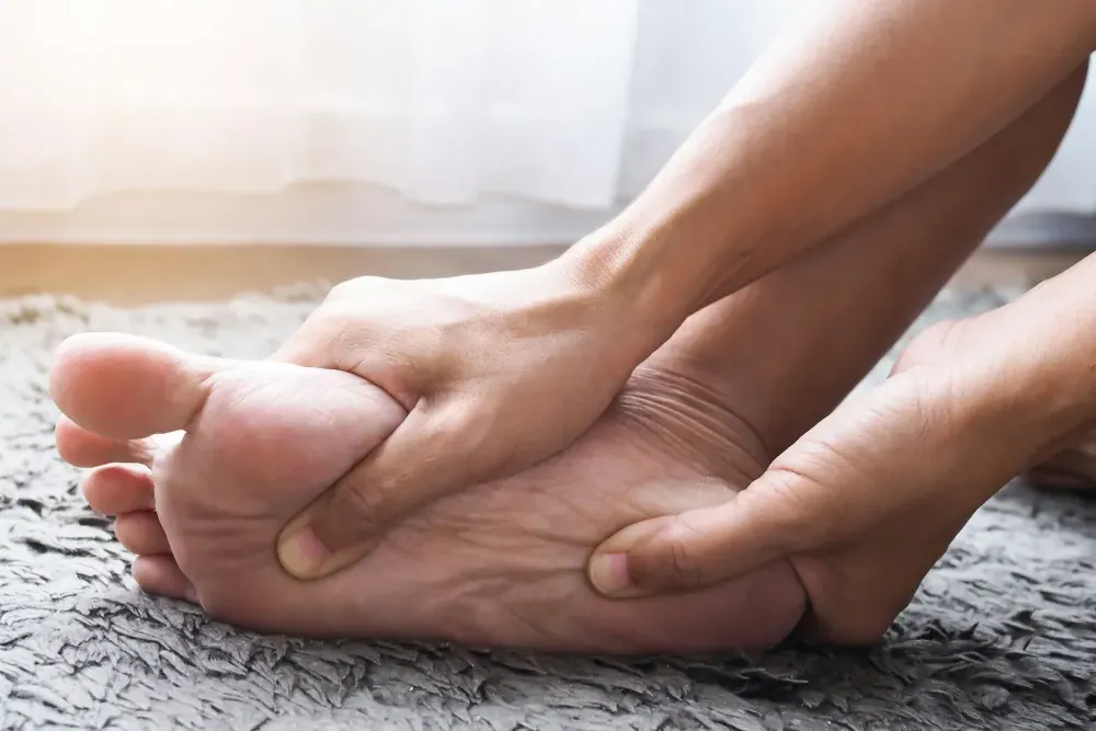 Person massaging a painful heel and arch from plantar fasciitis