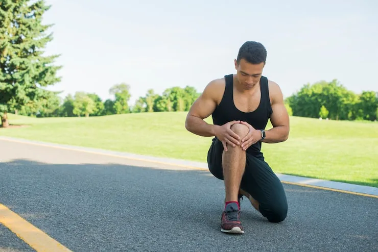 Runner kneeling and holding a painful knee
