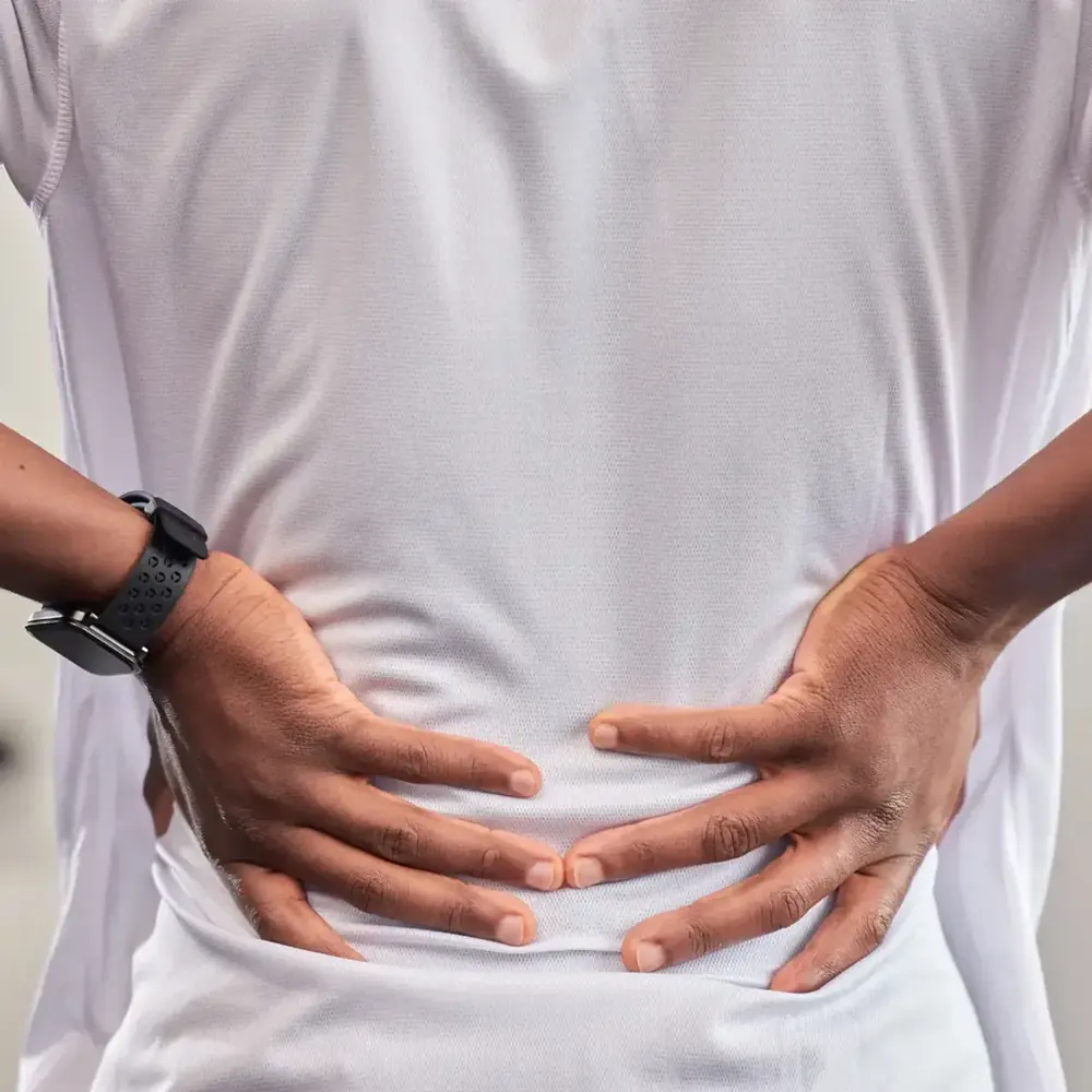 Person holding their lower back in pain from sciatica